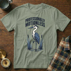 Green t-shirt with a heron graphic and text "PROFESSIONALLY MOTIONLESS".