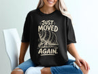 Black t-shirt with graphic of hermit crab and text "JUST MOVED AGAIN."