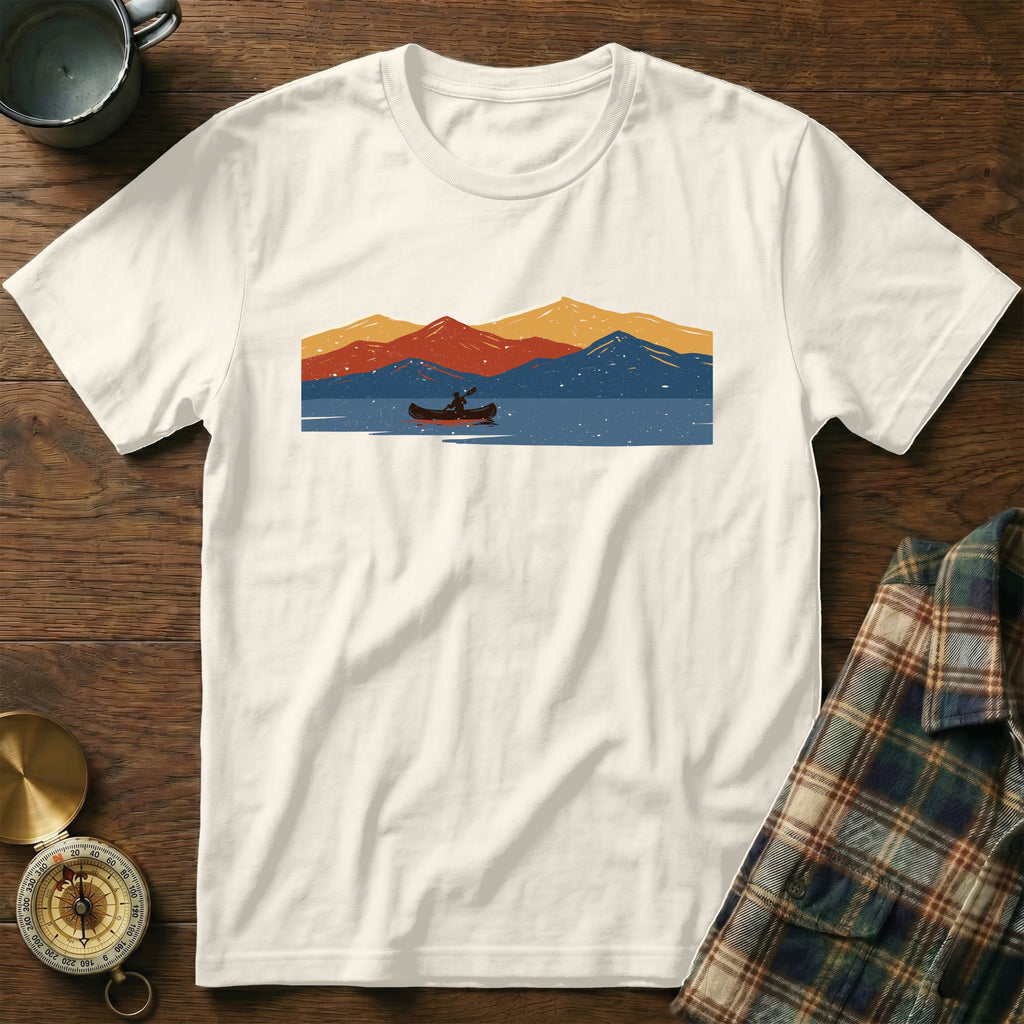 White t-shirt with a graphic of a canoeist on a lake with abstract mountains.