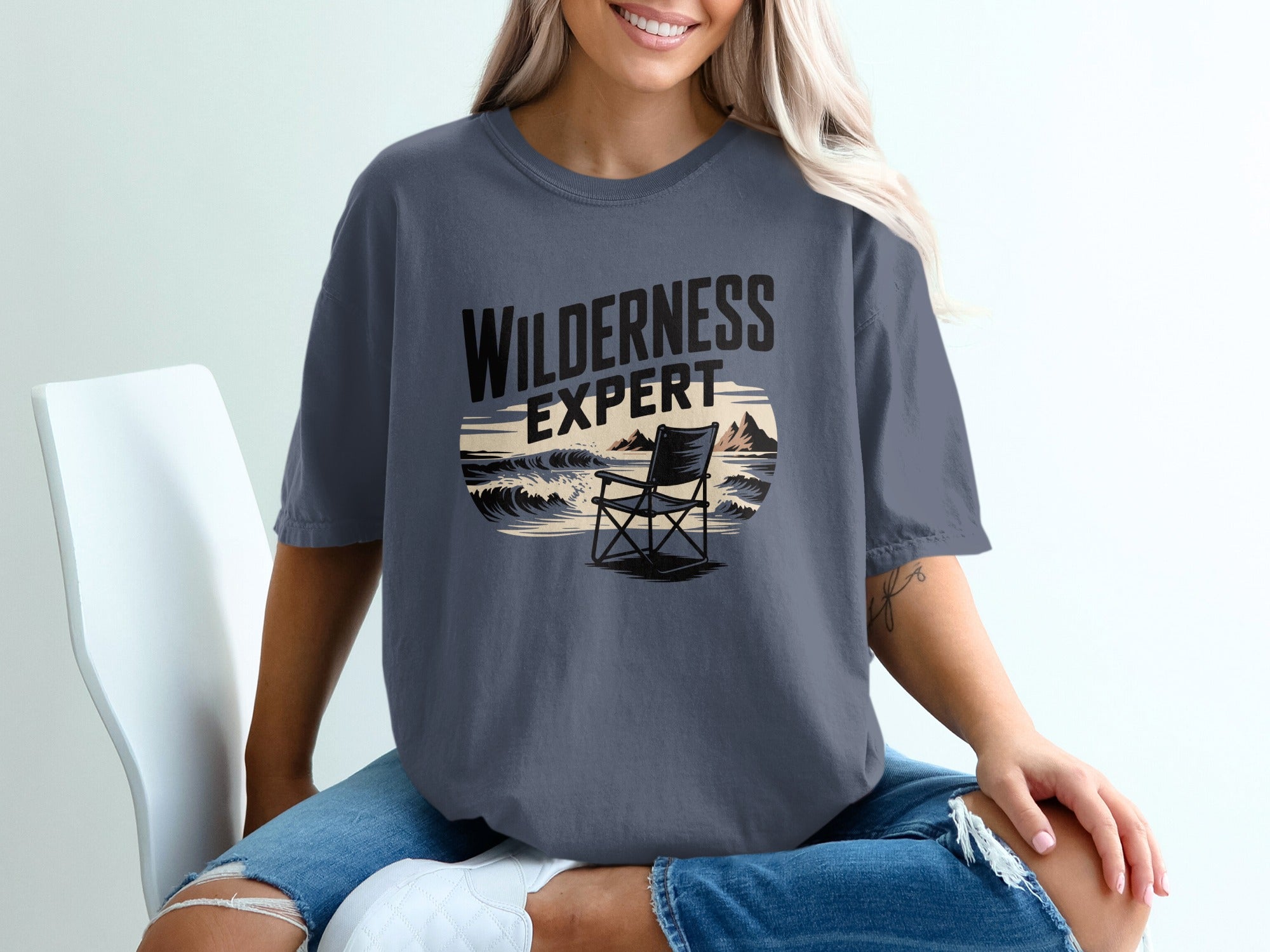 Dark gray t-shirt with "WILDERNESS EXPERT" text and beach scene graphic.