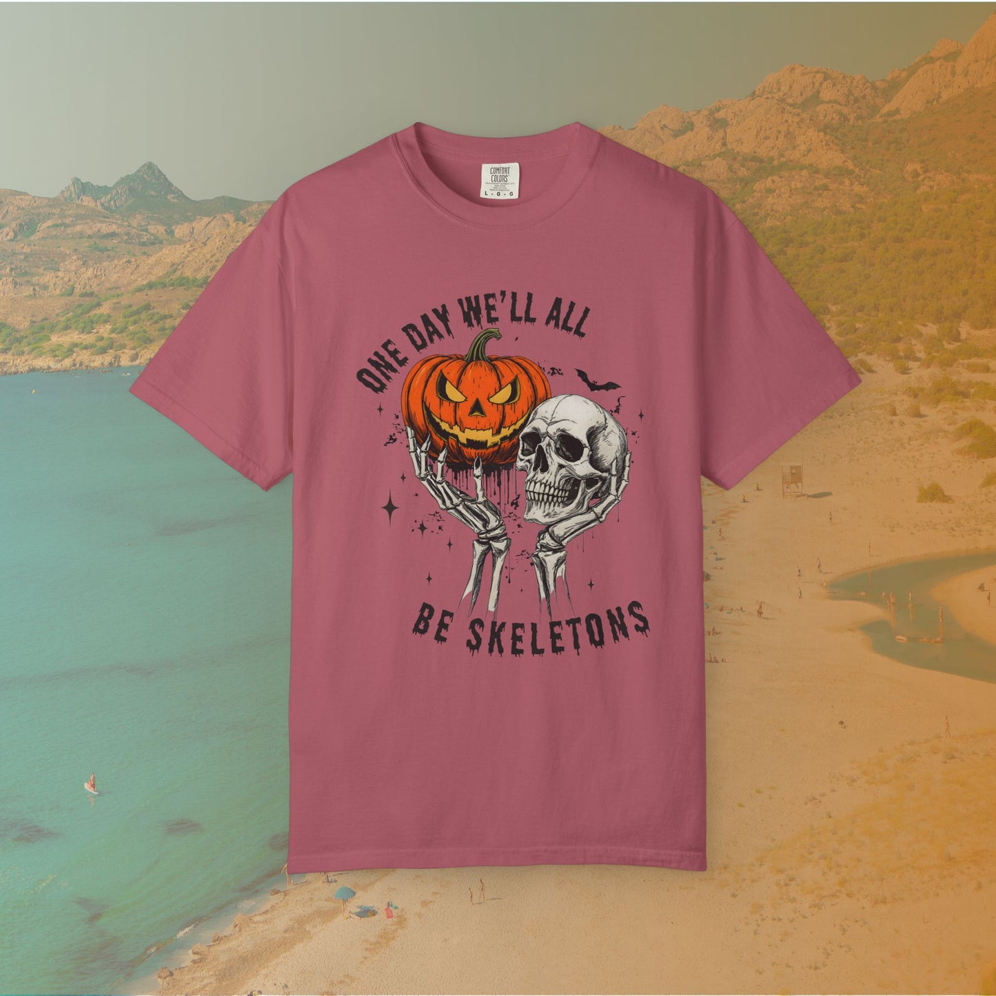 Skeleton hands holding a jack-o'-lantern and skull with the phrase ‘One Day We’ll All Be Skeletons’ in grunge font