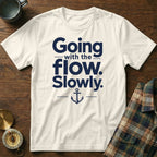 An off-white short-sleeved t-shirt features dark blue text reading "Going with the flow. Slowly." and an anchor graphic.