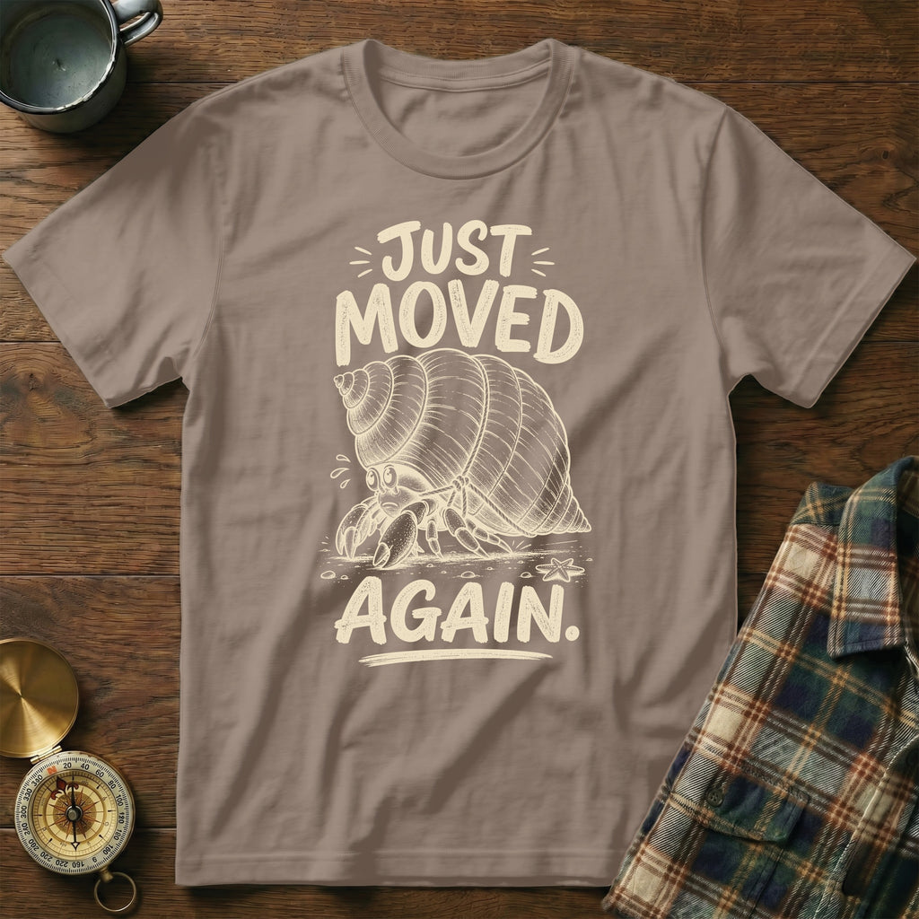 Hermit crab graphic on a taupe t-shirt with text "JUST MOVED AGAIN."