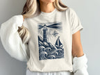 Cream t-shirt with navy lighthouse, sailboat, and waves graphic.