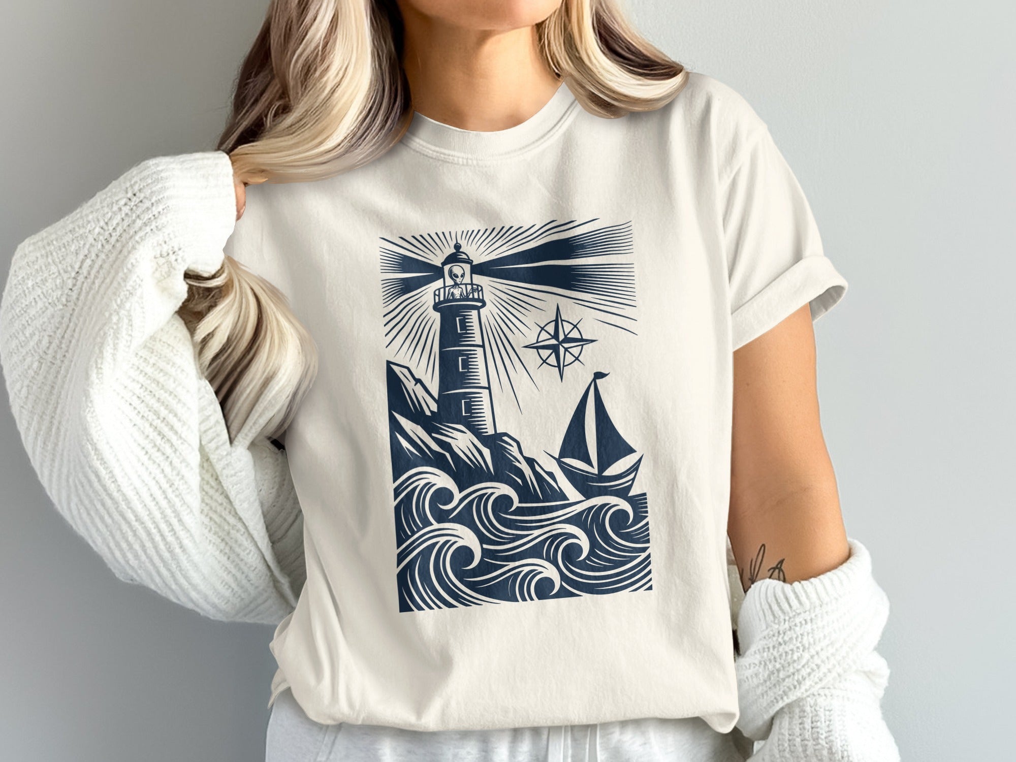 Cream t-shirt with navy lighthouse, sailboat, and waves graphic.