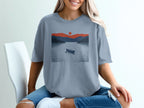 T-shirt with graphic of a canoe on a lake with mountains and a sunset.
