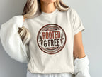 Cream t-shirt featuring a circular emblem with "ROOTED & FREE" text.