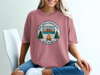 Retro "Adventure Awaits" graphic with cassette tape, trees, and campfire.