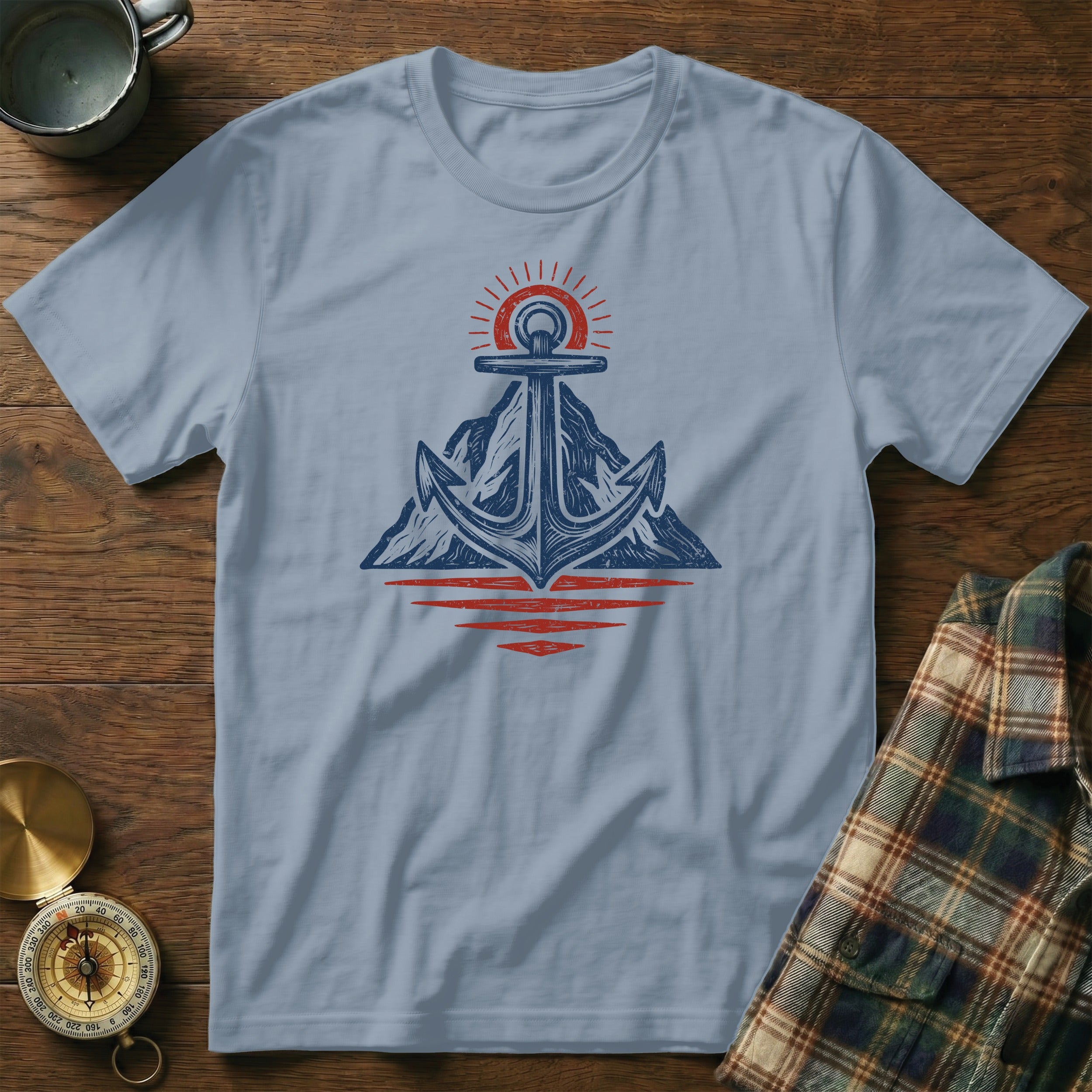 Anchor and mountain graphic on a light blue t-shirt with a sunrise motif.