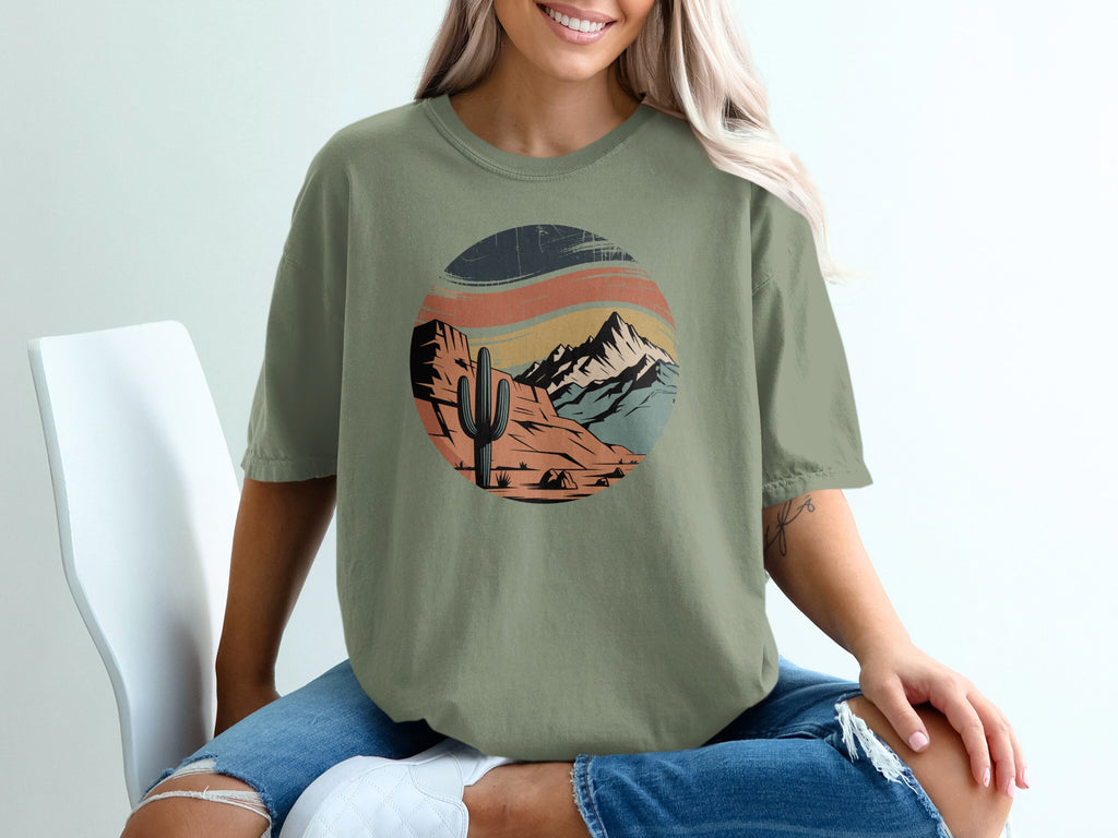 Green t-shirt with a retro desert landscape graphic featuring a cactus and mountains.