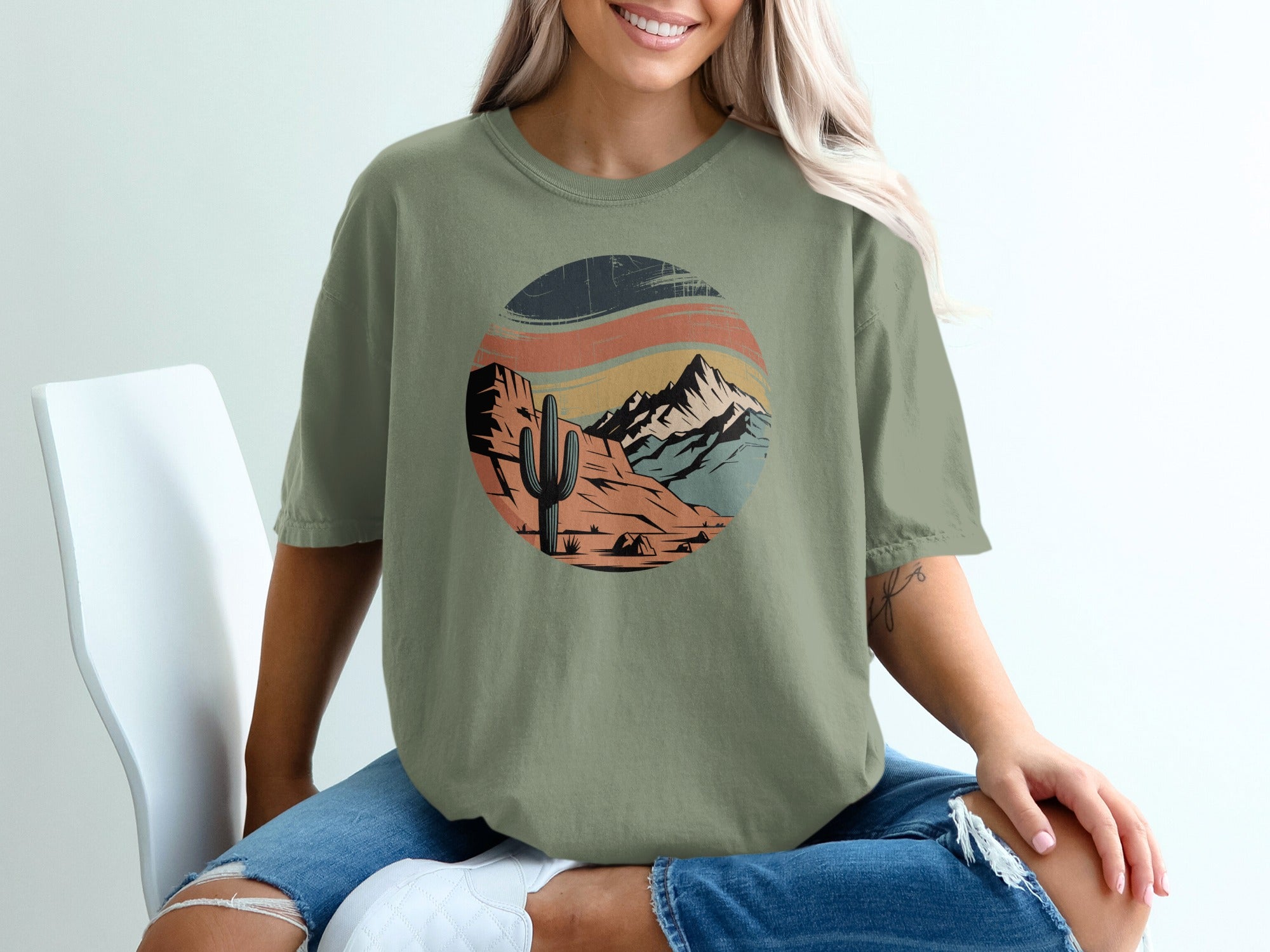 Green t-shirt with a retro desert landscape graphic featuring a cactus and mountains.