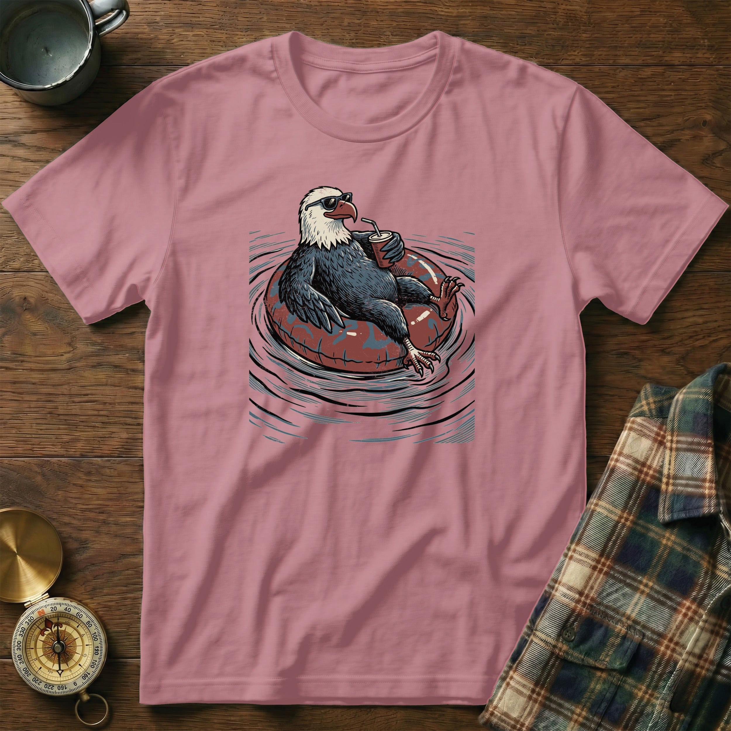 Bald eagle wearing sunglasses relaxes on an inflatable ring, holding a drink.