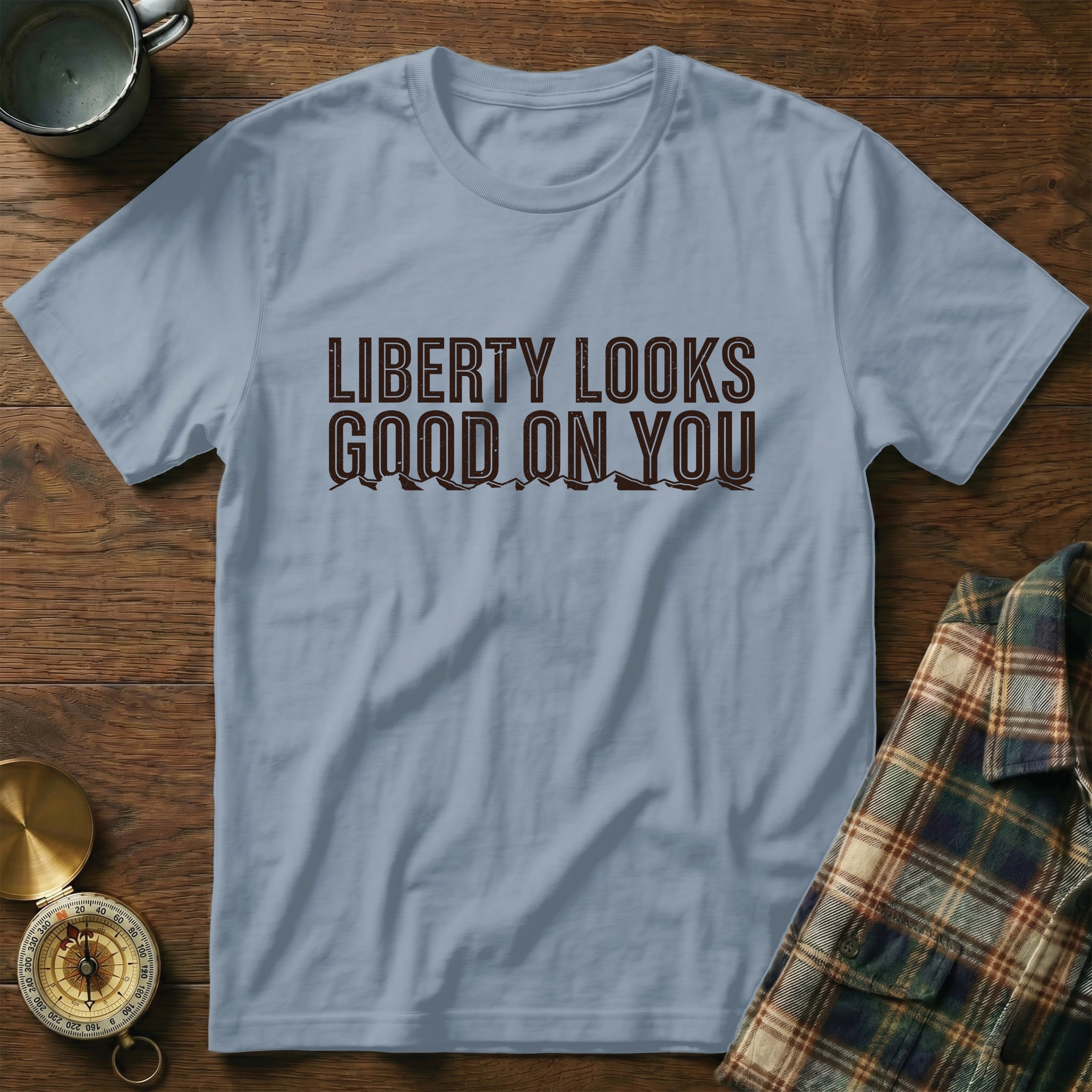 Light blue t-shirt with brown text "LIBERTY LOOKS GOOD ON YOU" and mountain graphic.