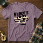 Purple t-shirt with "Wilderness Expert" text and camping chair on beach graphic.