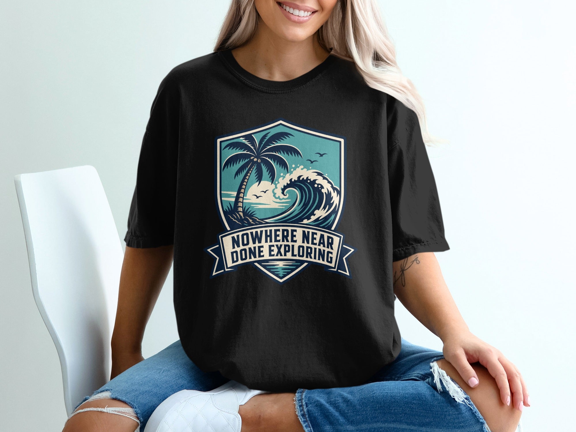 Black t-shirt with a beach scene graphic and text "Nowhere Near Done Exploring."