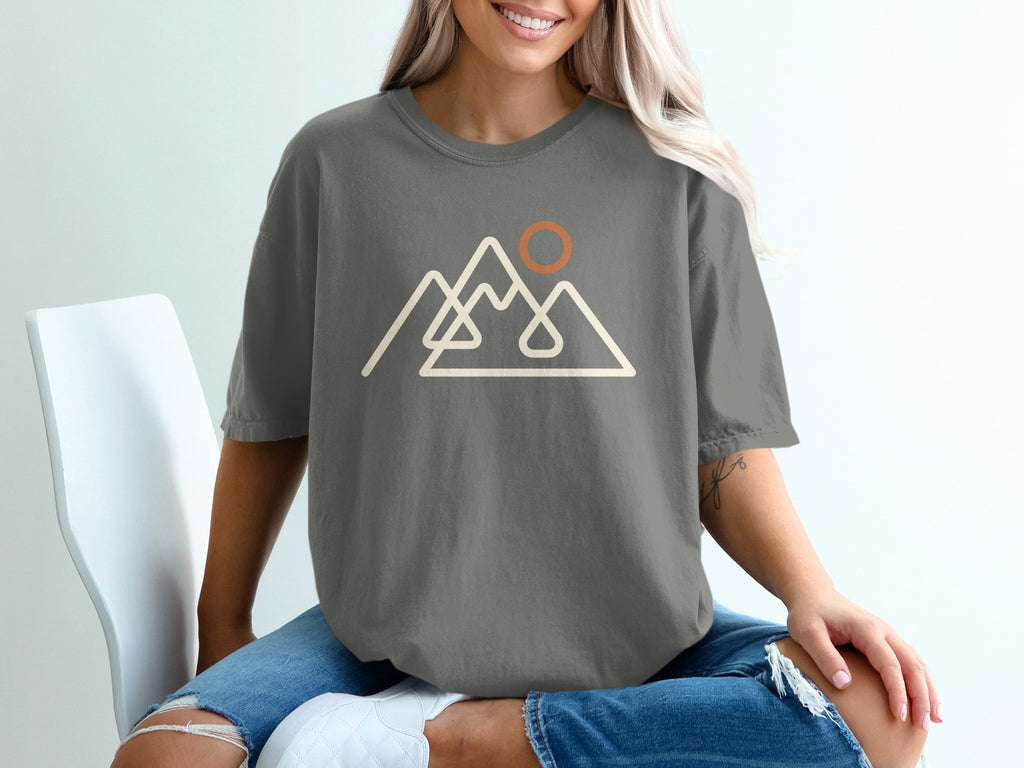Gray t-shirt with line art of mountains and a sun.