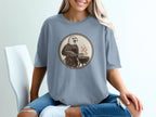 T-shirt graphic: bald eagle in apron grilling with tongs over barbecue.