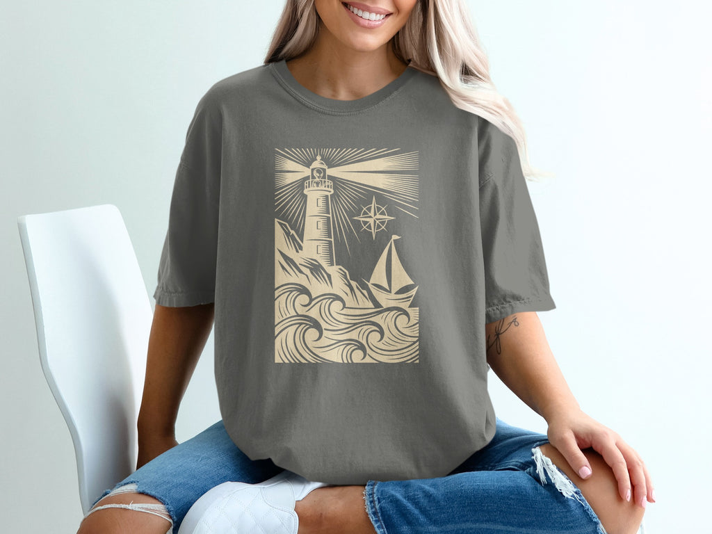 T-shirt graphic with lighthouse, sailboat, waves, and compass rose.