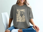 T-shirt graphic with lighthouse, sailboat, waves, and compass rose.