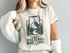 Cream t-shirt with nature graphic and text "Less Scroll. More Stroll."