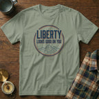 Olive green t-shirt with "LIBERTY LOOKS GOOD ON YOU" text and mountain graphic.