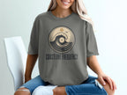 Gray t-shirt with circular wave and sun graphic and "Coastline Frequency" text.