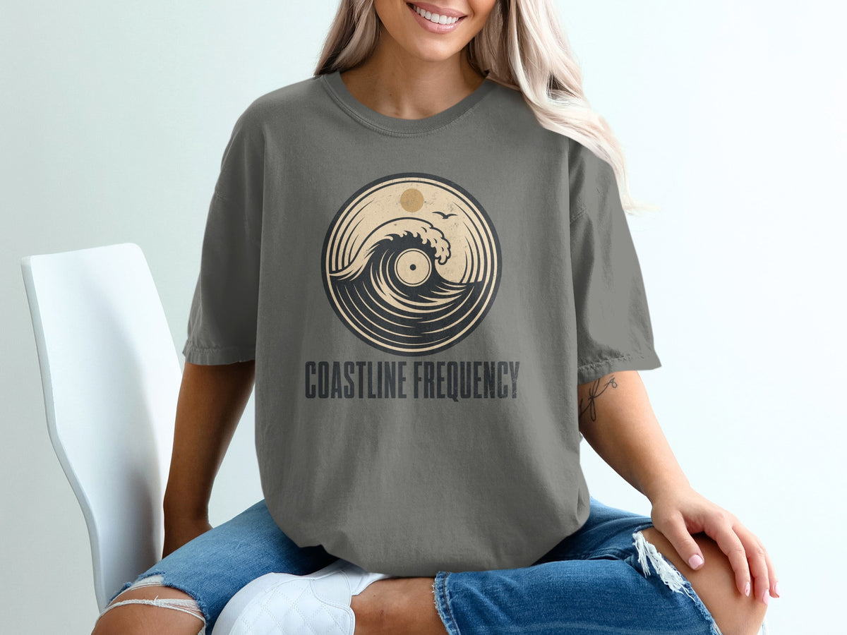 Gray t-shirt with circular wave and sun graphic and "Coastline Frequency" text.