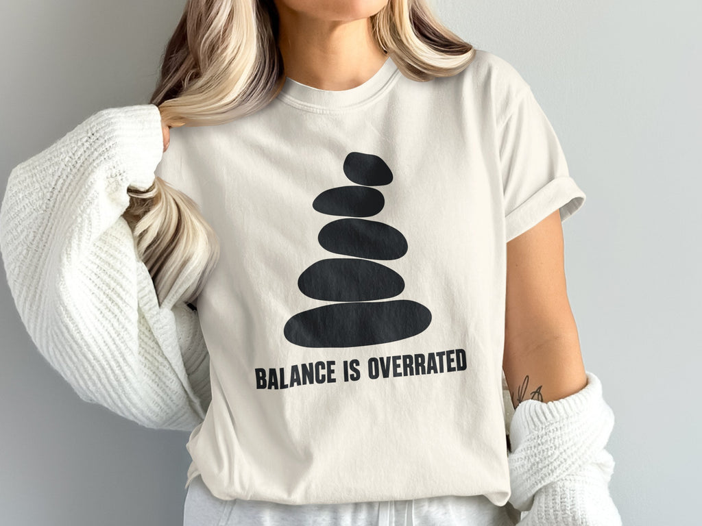 T-shirt with stacked stones graphic and "BALANCE IS OVERRATED" text.