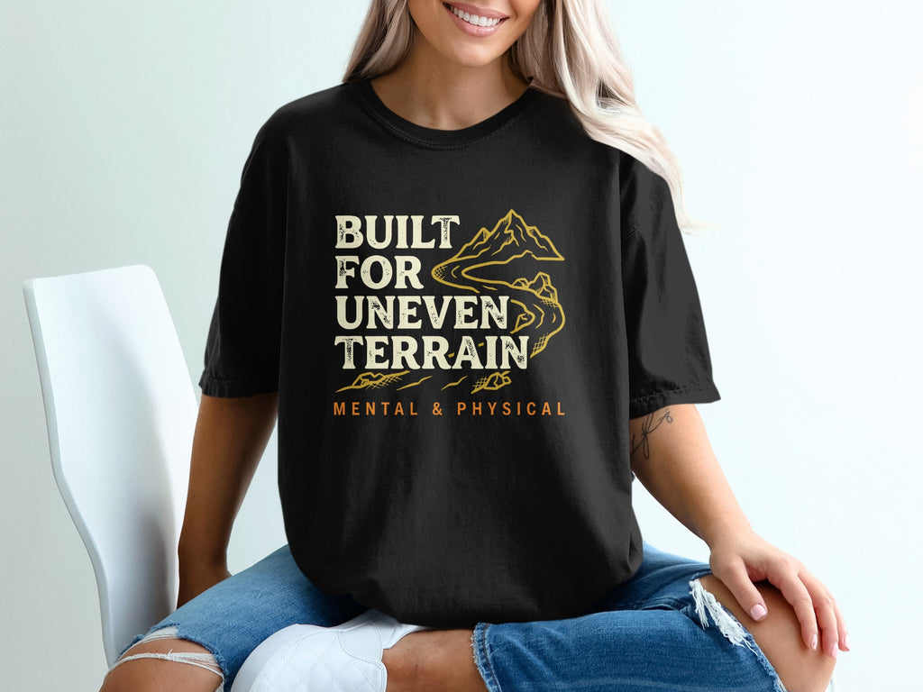 Black t-shirt with mountain graphic and text "BUILT FOR UNEVEN TERRAIN MENTAL & PHYSICAL".