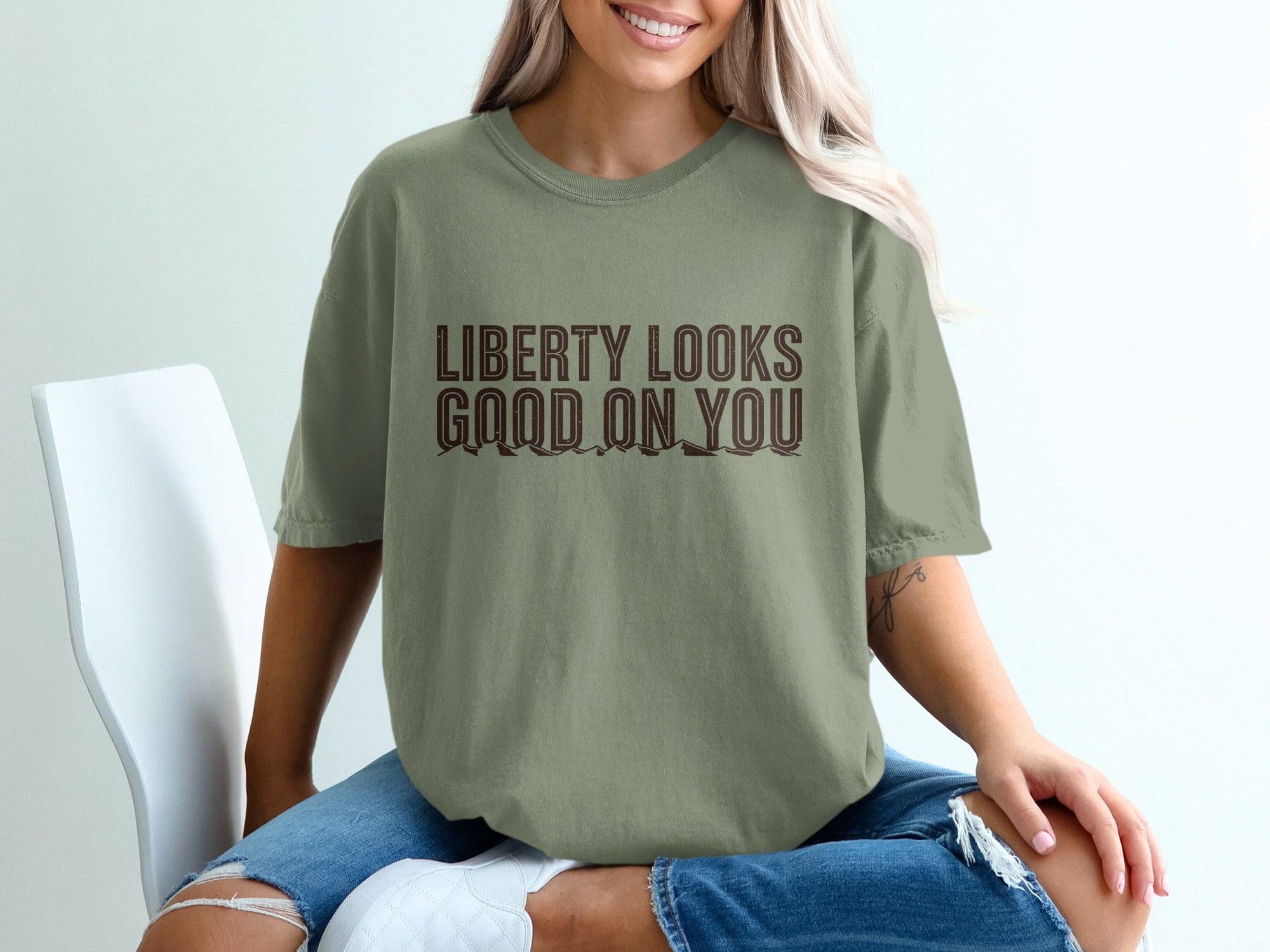Khaki t-shirt with brown text that reads "LIBERTY LOOKS GOOD ON YOU."