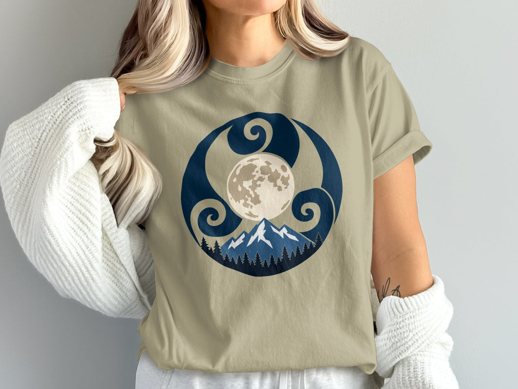 Tan t-shirt with moon, mountains, and trees graphic within a circular design.