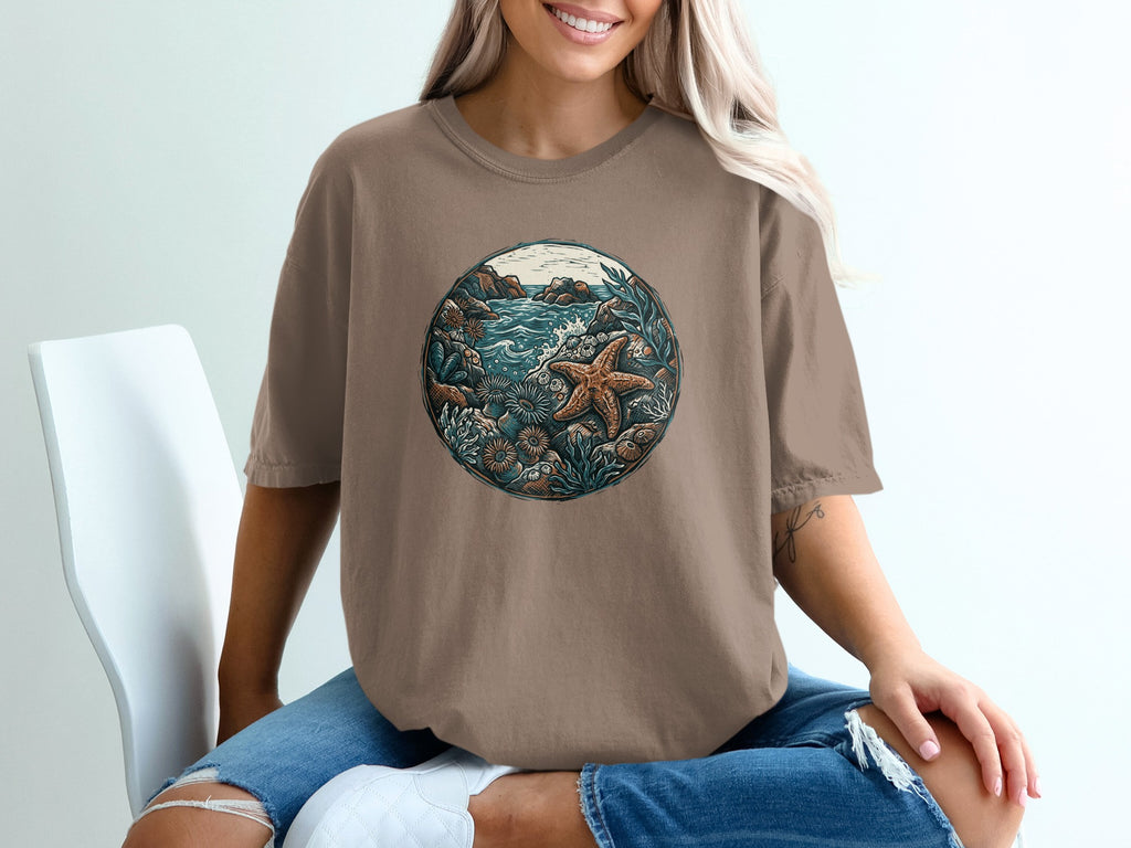 Brown t-shirt with circular nature graphic featuring starfish, rocks, and ocean plants.