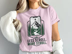 Pink t-shirt with "Less Scroll. More Stroll." text and nature graphic.