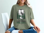 Green t-shirt with a smartphone screen graphic of a mountain and forest. "LESS SCROLL. MORE STROLL." text below.