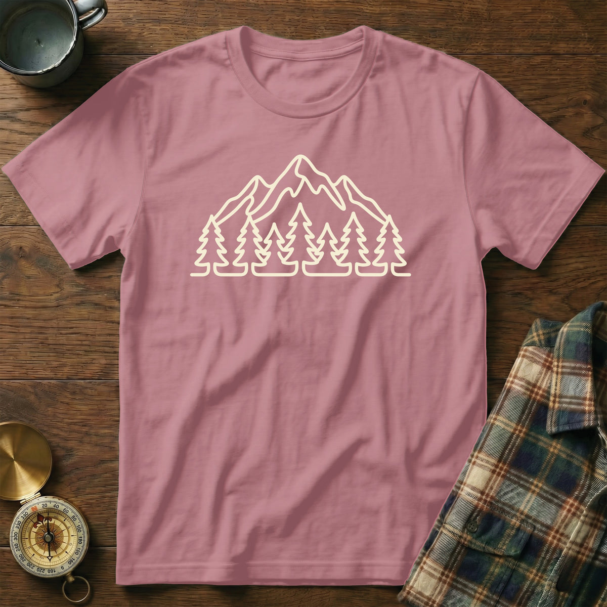 Pink t-shirt with a cream outline graphic of mountains and pine trees.