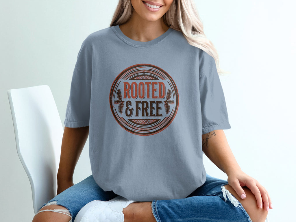 T-shirt with circular graphic reading "ROOTED & FREE" with leafy accents.