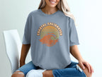 Grey t-shirt with "Coastal Calibrated" text and a sunset wave graphic.