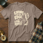 T-shirt with text "Living on the edge, barely" and a goat hanging from a cliff.