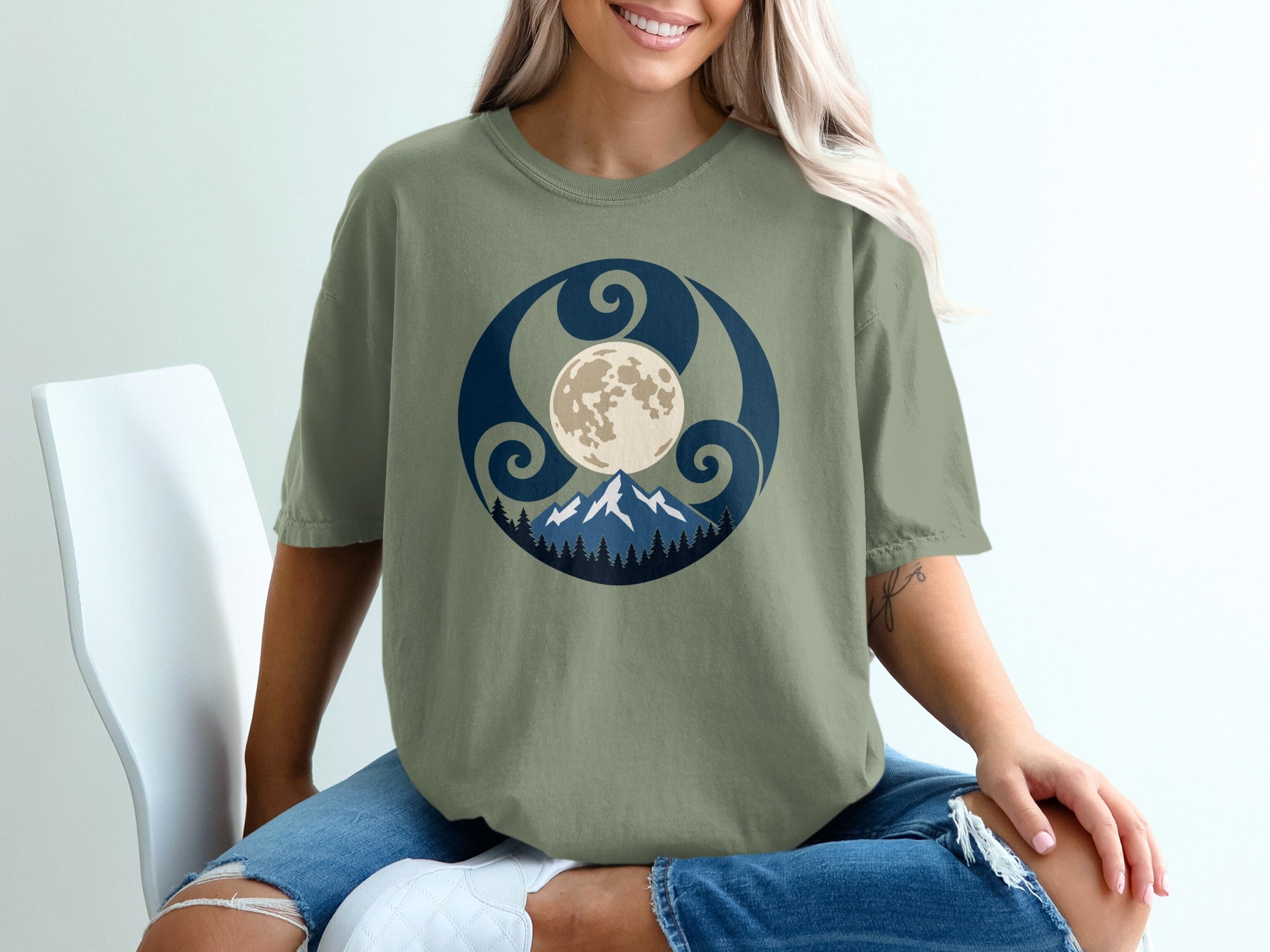 Green t-shirt with a circular graphic featuring mountains, trees, and a moon.