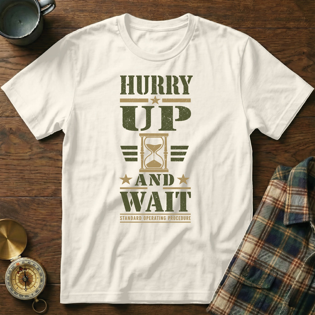 White t-shirt with green text reading HURRY UP AND WAIT and an hourglass graphic.