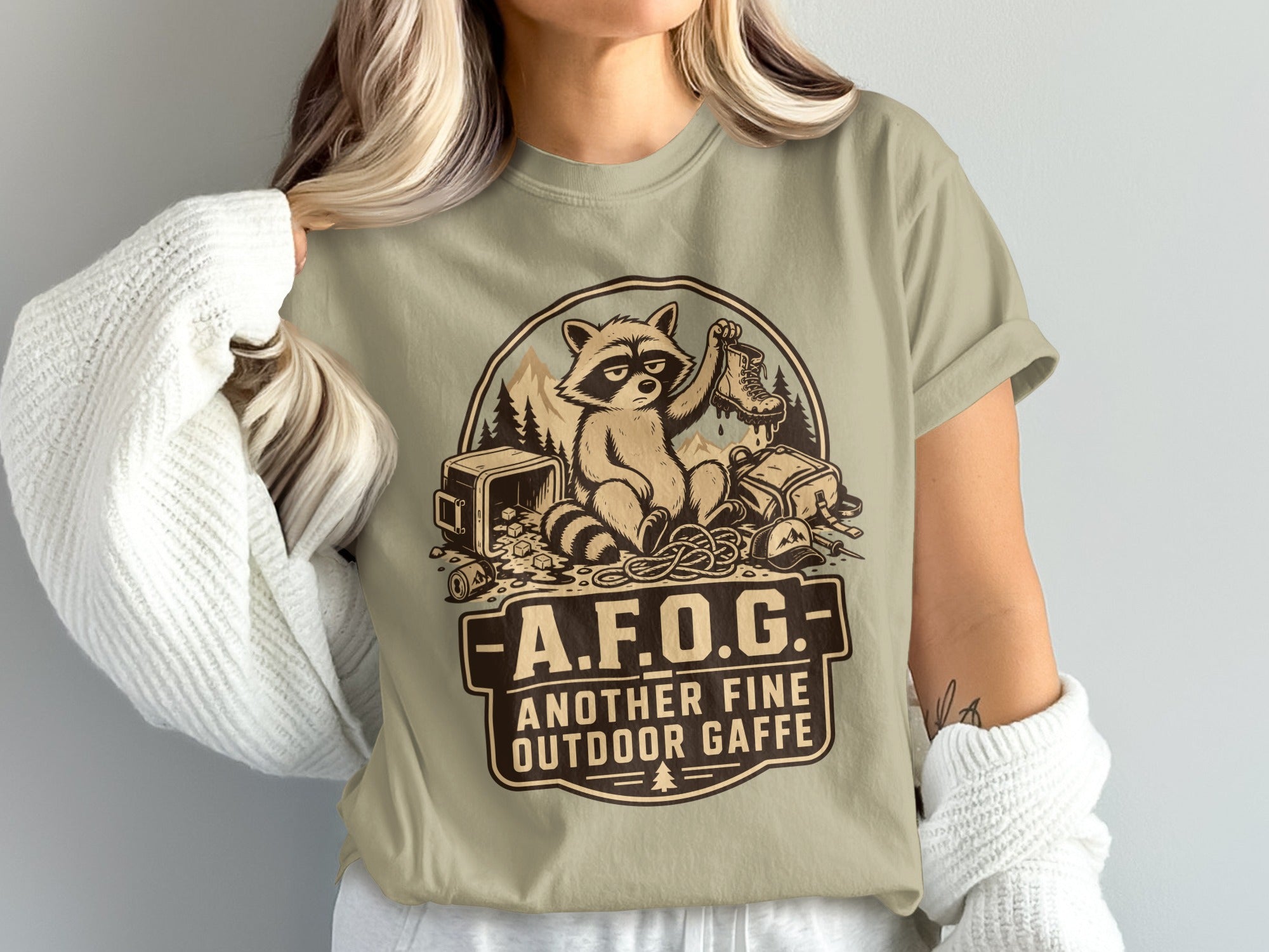 Raccoon holding a boot with text "A.F.O.G. Another Fine Outdoor Gaffe".
