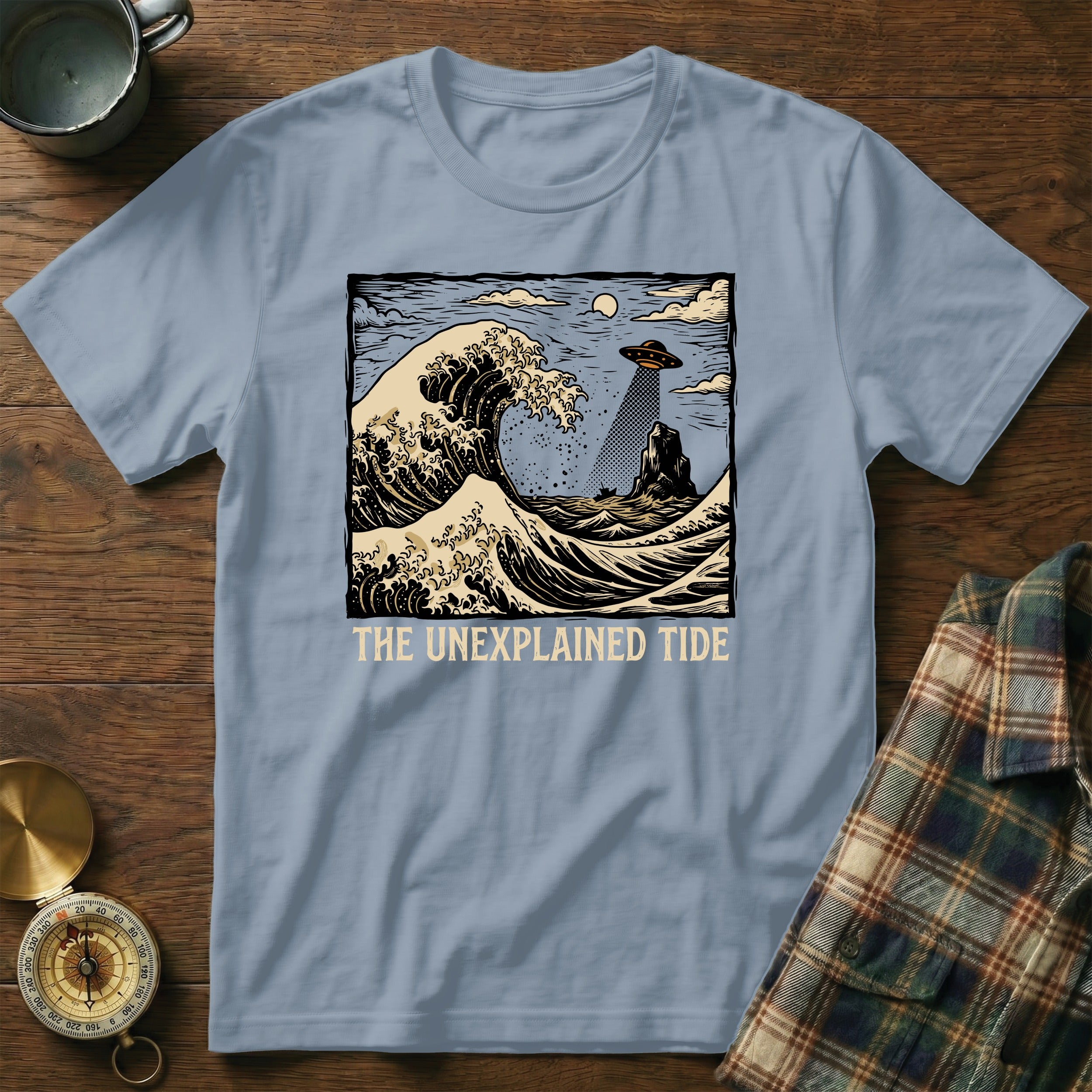 T-shirt with "The Unexplained Tide" text and a wave with a UFO.