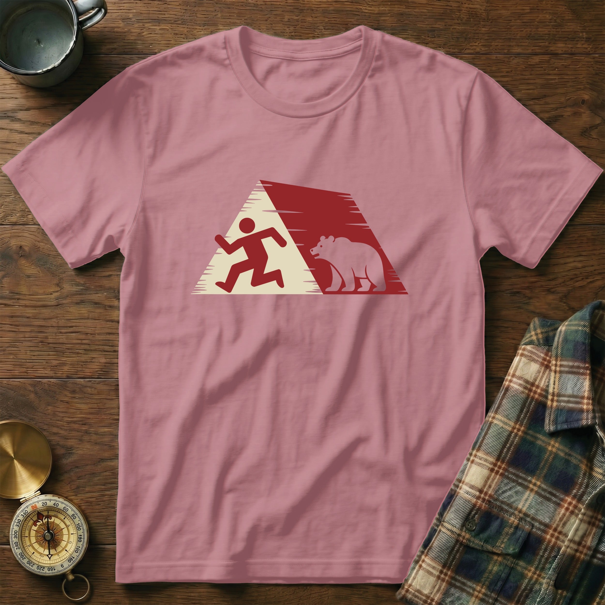 Running figure and bear silhouetted against a mountain range graphic on a pink t-shirt.