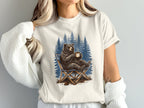 Bear sitting in a camping chair holding a coffee mug with trees behind it.