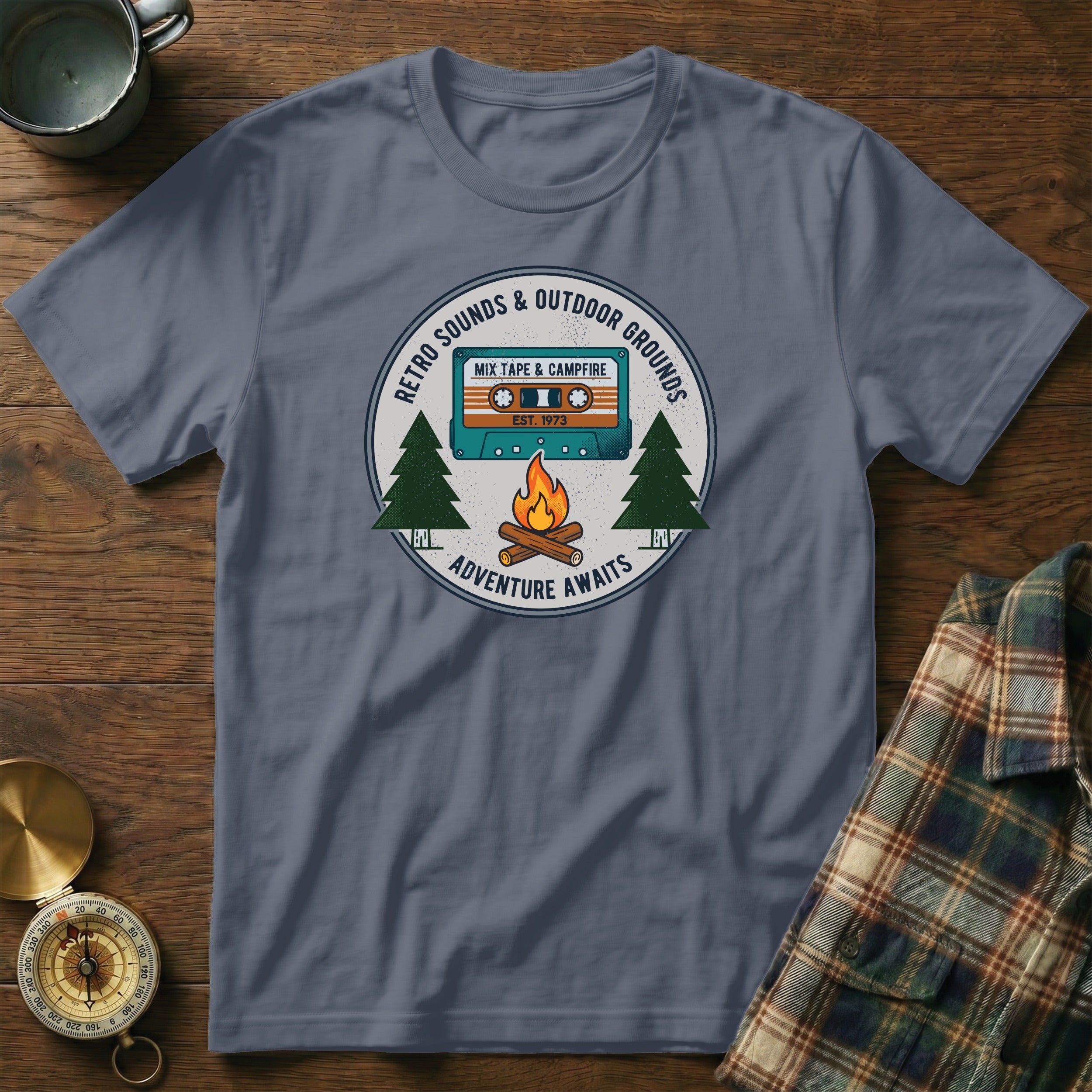 T-shirt graphic with retro cassette, campfire, trees, and text.