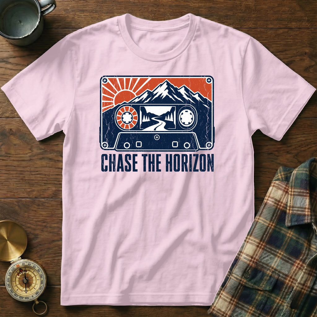 Pink t-shirt with a cassette tape graphic featuring mountains, sun, and road, text "CHASE THE HORIZON".