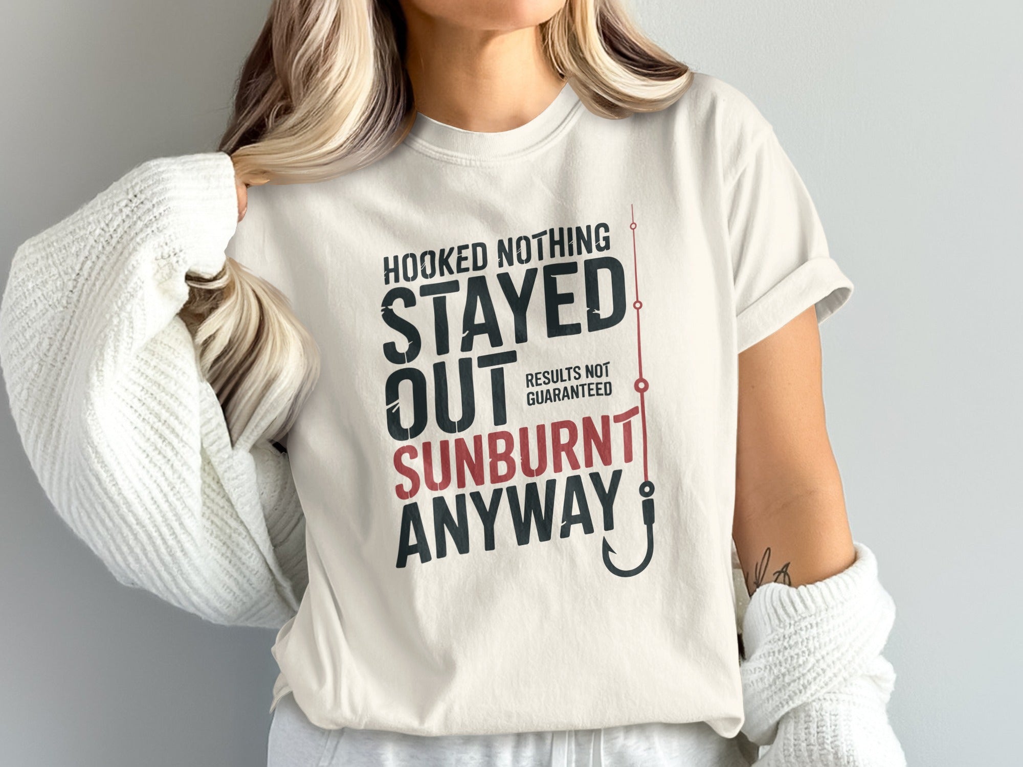 Cream t-shirt with "HOOKED NOTHING STAYED OUT SUNBURNT ANYWAY RESULTS NOT GUARANTEED" text.