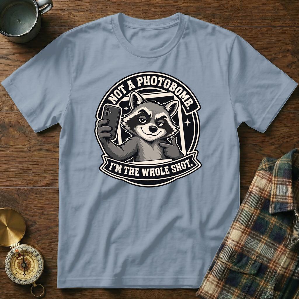 Light blue t-shirt featuring a raccoon taking a selfie with text "Not a photobomb. I'm the whole shot."