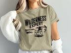 T-shirt with "WILDERNESS EXPERT" text and camping chair graphic.