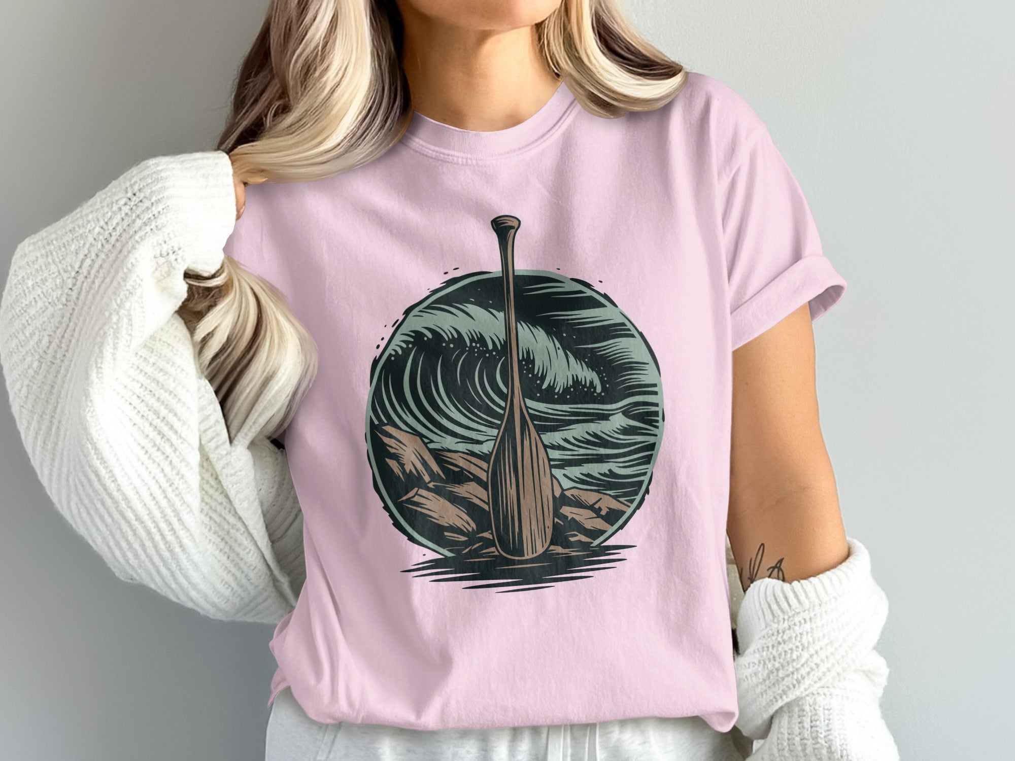 T-shirt featuring a wooden oar against a backdrop of waves and rocks.